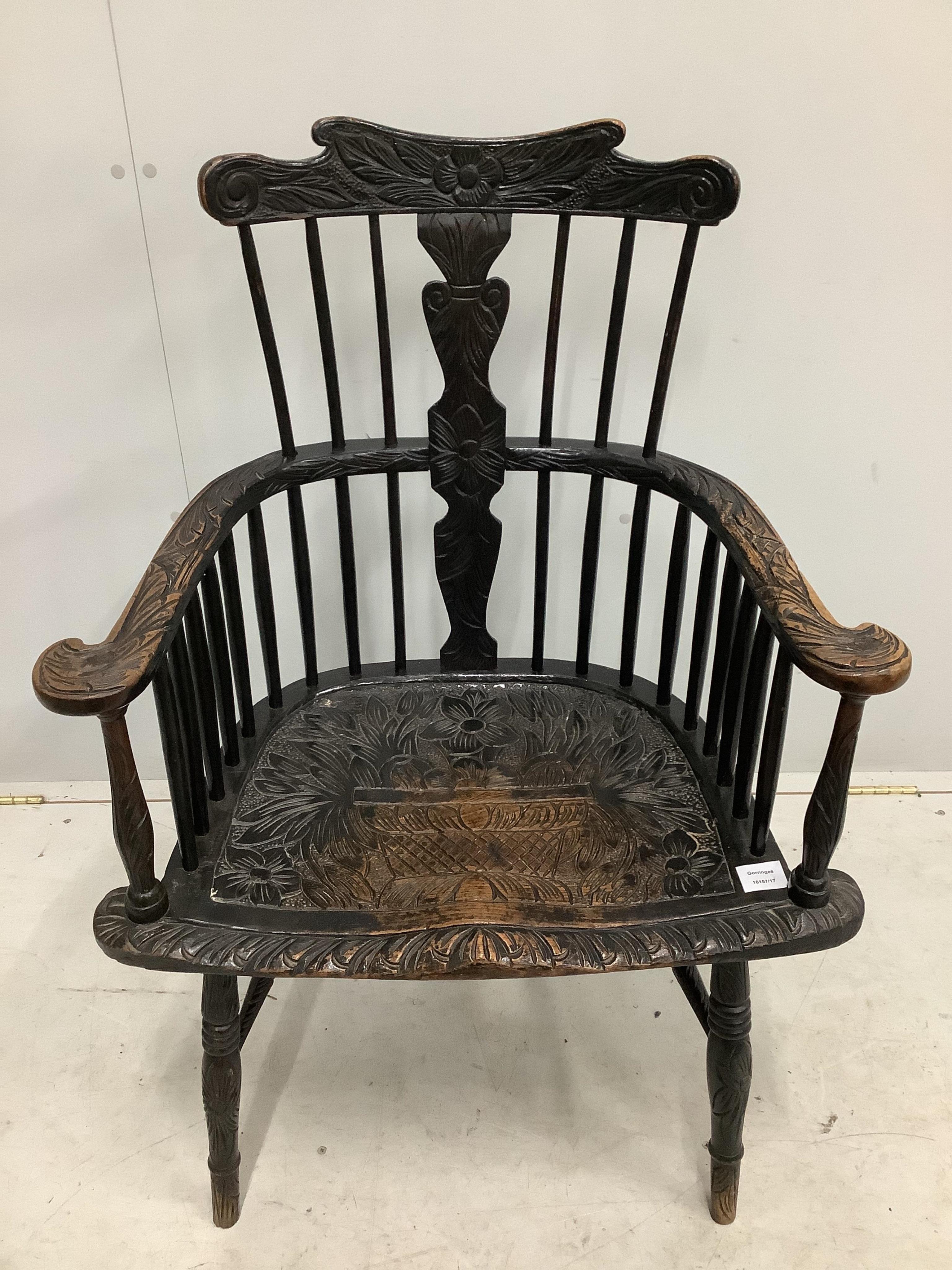 A 19th century Windsor comb back elbow chair, later stained and carved, width 69cm, depth 45cm, height 101cm. Condition - fair to good